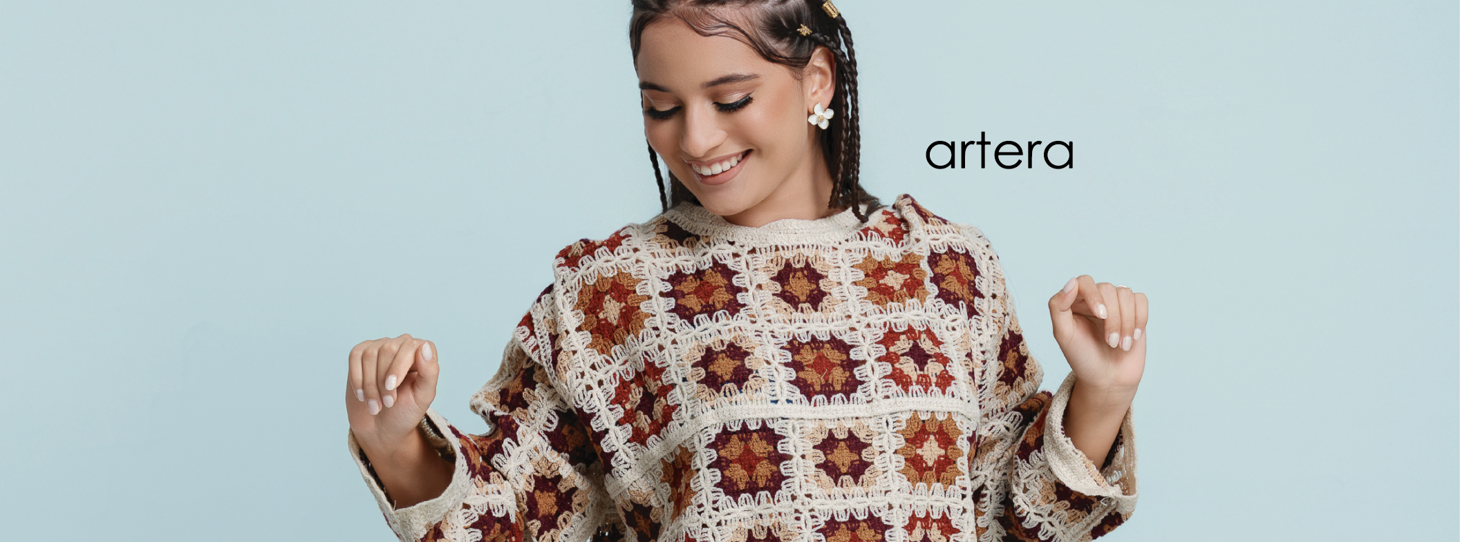 Woman wearing a patterned sweater and denim shorts on a light blue background with 'artera' branding.